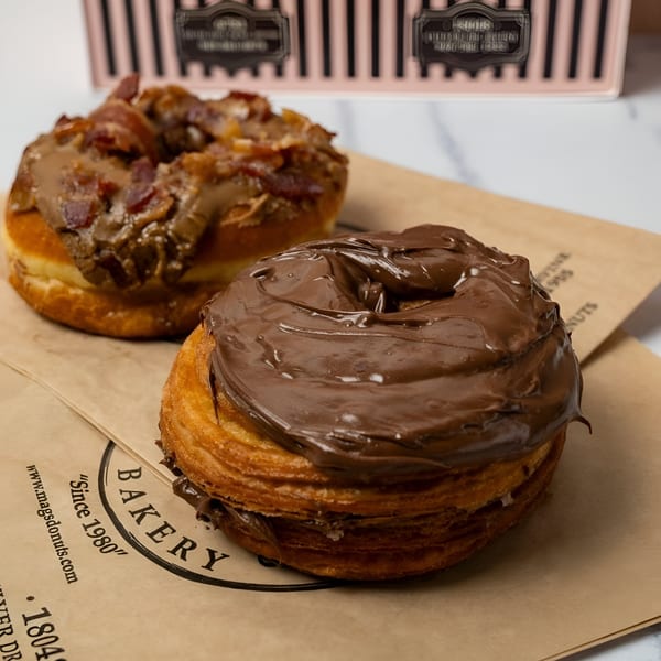 Two Mag's Donuts cronuts, one with chocolate frosting and the other with bacon and frosting.